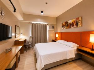 a hotel room with a bed and a flat screen tv at MIGAs Haven at Sunvida Tower across SM City in Cebu City