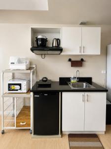 a small kitchen with white cabinets and a sink at MIGAs Haven at Sunvida Tower across SM City in Cebu City +31 photos