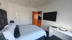 a bedroom with a white bed and a flat screen tv at Executive Sea View Apartment in Glencairn +4 photos