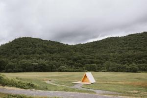 a small structure in a field with a mountain at Otherland Hotel in Newfane