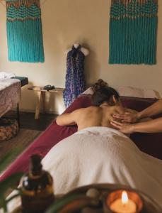 a woman laying on a bed with a candle at Meno Lagoon Bungalows in Gili Meno