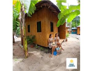 two women sitting in front of a small building at Point Calixto beach front hut, Boracay in Boracay