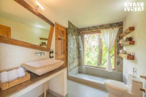 a bathroom with a sink and a toilet and a window at StayVista at Sukoon Nature Retreat in Bhatrojkhan
