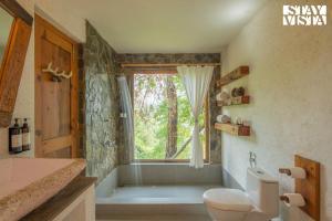 a bathroom with a tub and a toilet and a window at StayVista at Sukoon Nature Retreat in Bhatrojkhan +40 photos