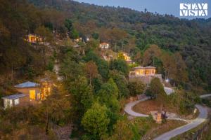 an aerial view of a house on a hill with a winding road at StayVista at Sukoon Nature Retreat in Bhatrojkhan