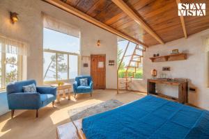 a bedroom with a bed and two chairs and a fireplace at StayVista at Sukoon Nature Retreat in Bhatrojkhan