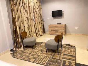 a living room with two chairs and a television at Peach City Hotel in Prampram