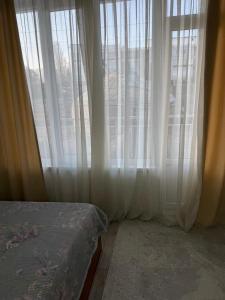 a bedroom with a large window with white curtains at Квартира студия in Bosteri