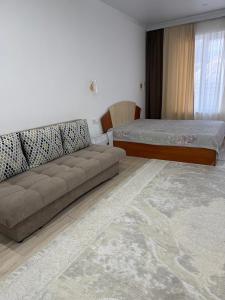 a living room with a couch and a bed at Квартира студия in Bosteri