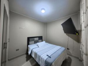 a white bedroom with a bed and a television at Esencia de Altura Hostal in El Tambo