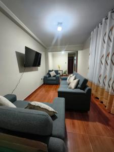 a living room with two couches and a flat screen tv at Esencia de Altura Hostal in El Tambo