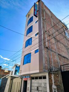 a tall white building with a sign on it at Esencia de Altura Hostal in El Tambo