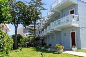 a white building with trees in the yard at Posidonia Pension in Amarynthos