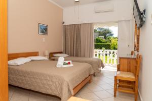 a bedroom with two beds and a balcony at Posidonia Pension in Amarynthos