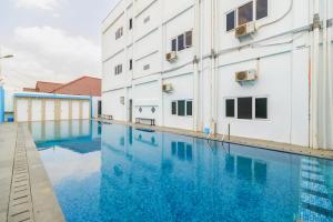 a swimming pool in front of a building at RedDoorz Plus near Palembang Icon Mall 2 in Palembang