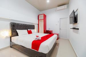a bedroom with a large bed and a television at RedDoorz Plus near Palembang Icon Mall 2 in Palembang +18 photos
