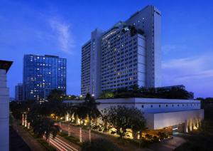 a tall building with lights in front of a street at New World Makati Hotel, Manila in Manila