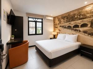 a hotel room with a bed and a tv at Hotel Habitat San Antonio in Cali