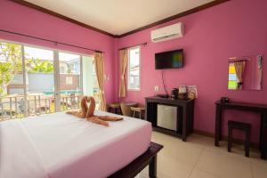 a bedroom with a pink wall with a bed and a tv at ไข่ปูพูลเกาะล้าน in Ko Larn
