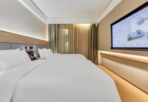 a hotel room with a bed and a flat screen tv at JI Hotel Beijing Panjiayuan in Beijing
