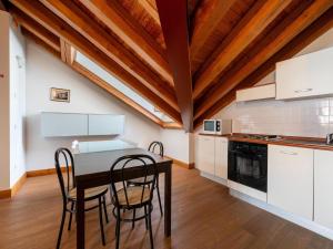 a kitchen with white cabinets and a table and chairs at Attic historic building with air conditioning in Ceresole Reale
