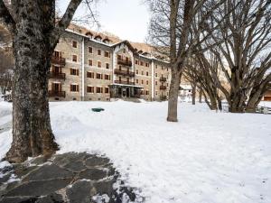 a building in the snow with trees in front of it at Attic historic building with air conditioning in Ceresole Reale