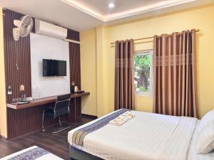 a hotel room with a bed and a desk and a television at Yula Hotel in Vientiane