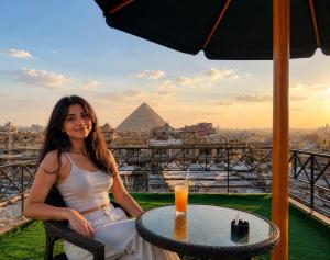 a woman sitting at a table with a view of the pyramid at Families Pyramids view - Rooftop in Cairo