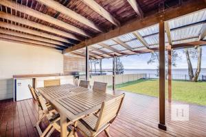 a dining room with a table and chairs on a deck at Sunrise Waters in Gorokan