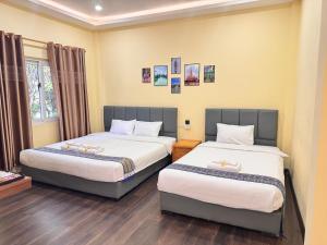 a bedroom with two beds and a window at Yula Hotel in Vientiane
