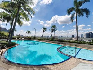a large swimming pool with palm trees on a building at The Emerald Hotel Bangkok Ratchada in Bangkok
