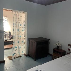a bedroom with a bed and a dresser and a curtain at La maison jaune in Nosy Be