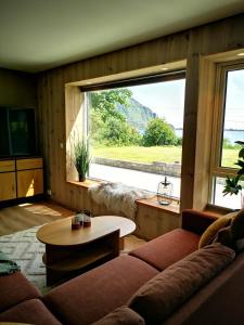 a living room with a couch and a table and a large window at Lofoten Seaview Apartment B in Sennesvik