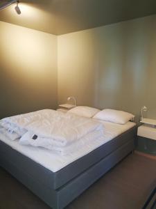 a bed with white sheets and pillows in a room at Lofoten Seaview Apartment B in Sennesvik