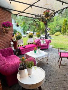 a patio with pink couches and tables with flowers at Willa Antyki24 nad Białym Jeziorem - Las in Sztum