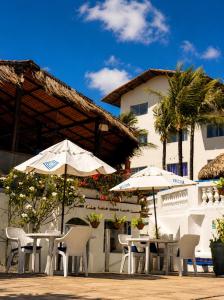 two tables and chairs with umbrellas in front of a building at La Suite Praia Hotel in Caucaia