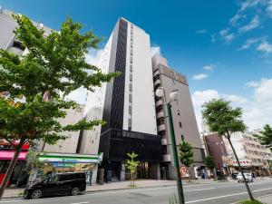 a tall white building on a city street at KOKO HOTEL Sapporo Susukino 2ⁿᵈ in Sapporo