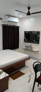 a bedroom with a bed and a tv and a chair at The Highway Haven in Silchar