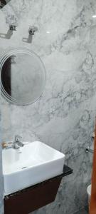 a bathroom with a white sink and a mirror at The Highway Haven in Silchar +11 photos