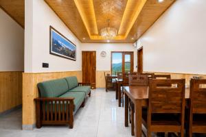 a restaurant with a green couch and wooden tables and chairs at The Dogri Boutique Cottage, Mashobra - Luxury Cottage with Scenic mountain view in Shimla