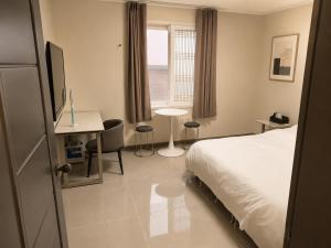 a bedroom with a bed and a desk and a window at New Star Hotel in Chu-sung