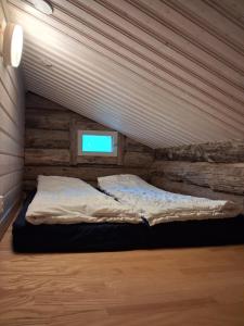 a bed in a room with a tv on the wall at Iso-Syöte tunnelmallinen kelomökki in Naamanka