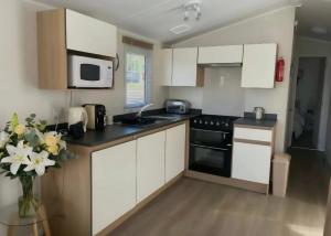 a kitchen with white cabinets and a sink and a microwave at Seashells - Exclusive Private Area to Side in Coldingham