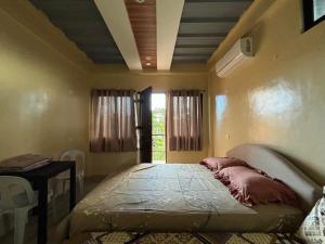a bedroom with a bed in a room with a window at W Island Backpackers Inn in Dauis