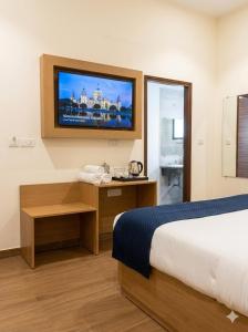 a hotel room with a bed and a television on the wall at JHS Kundli in Sonīpat +3 photos