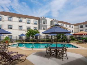 a hotel with a table and chairs and a pool at Hyatt House Boston/Burlington in Burlington