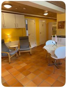 a living room with chairs and a table and a kitchen at Skøn perle midt i naturen in Munke Bjergby +12 photos