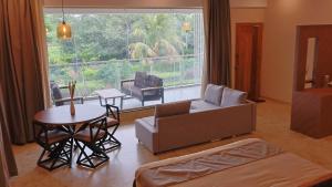 a living room with a couch and a table and a large window at Aadvik Luxury Farmstay in Antarasante
