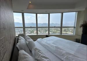 a bed in a room with a large window at Whispers above the city 2Bhk Centaurus Mall pool Gym City view in Islamabad +29 photos