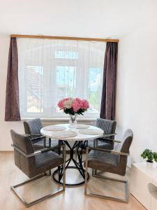 a table with chairs and a vase of flowers at Hostel am Rhein - Nierstein in Nierstein +2 photos